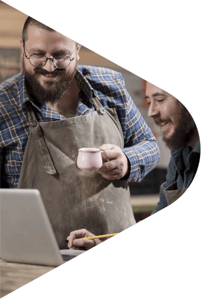 Two craftspeople looking at a laptop together in their workshop